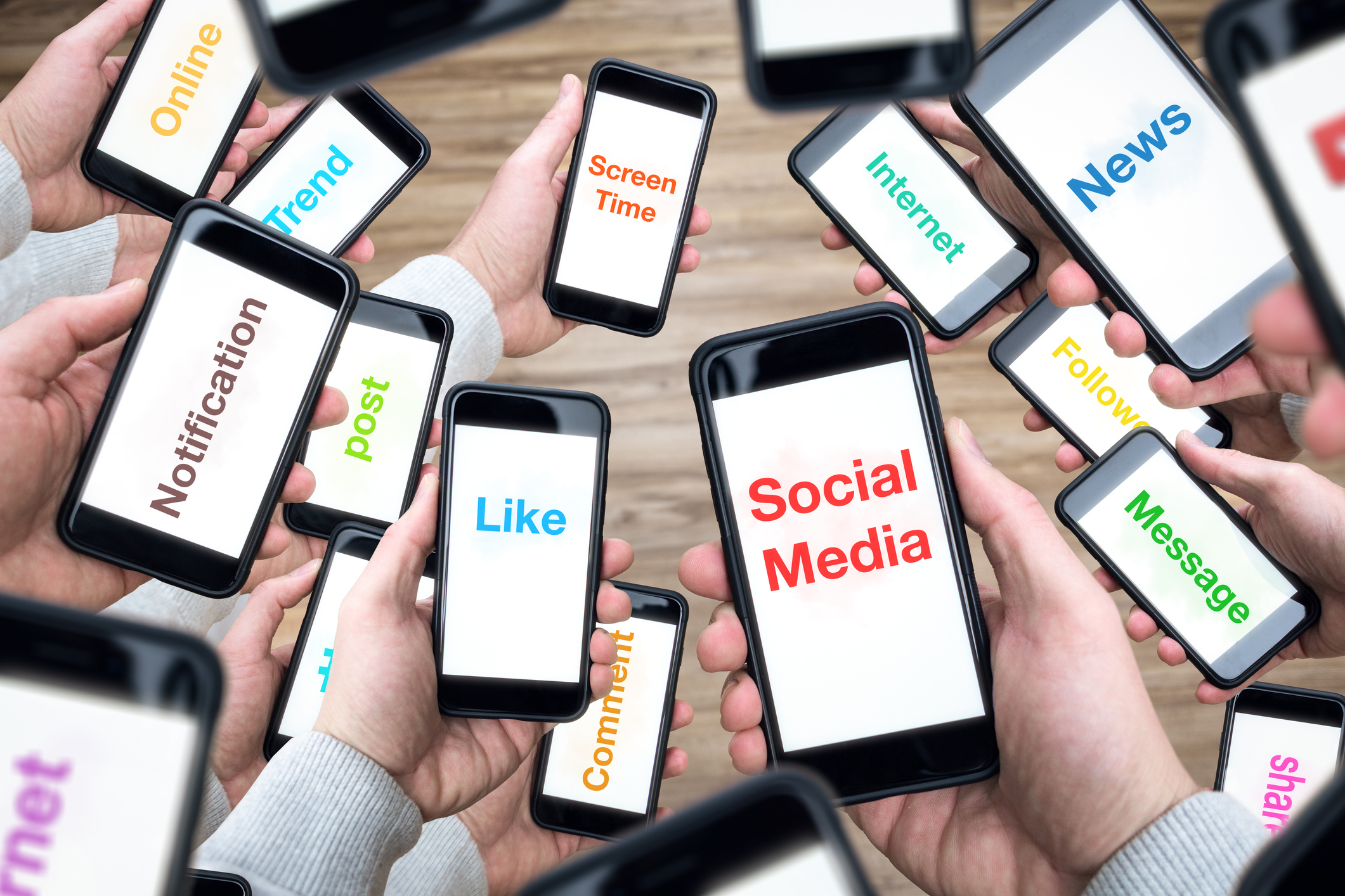Stock Image of a Multitude Of Hands Holding Cell Phones with Words on the Screens Such As Social Media Like Notification Message Screen Time News Internet