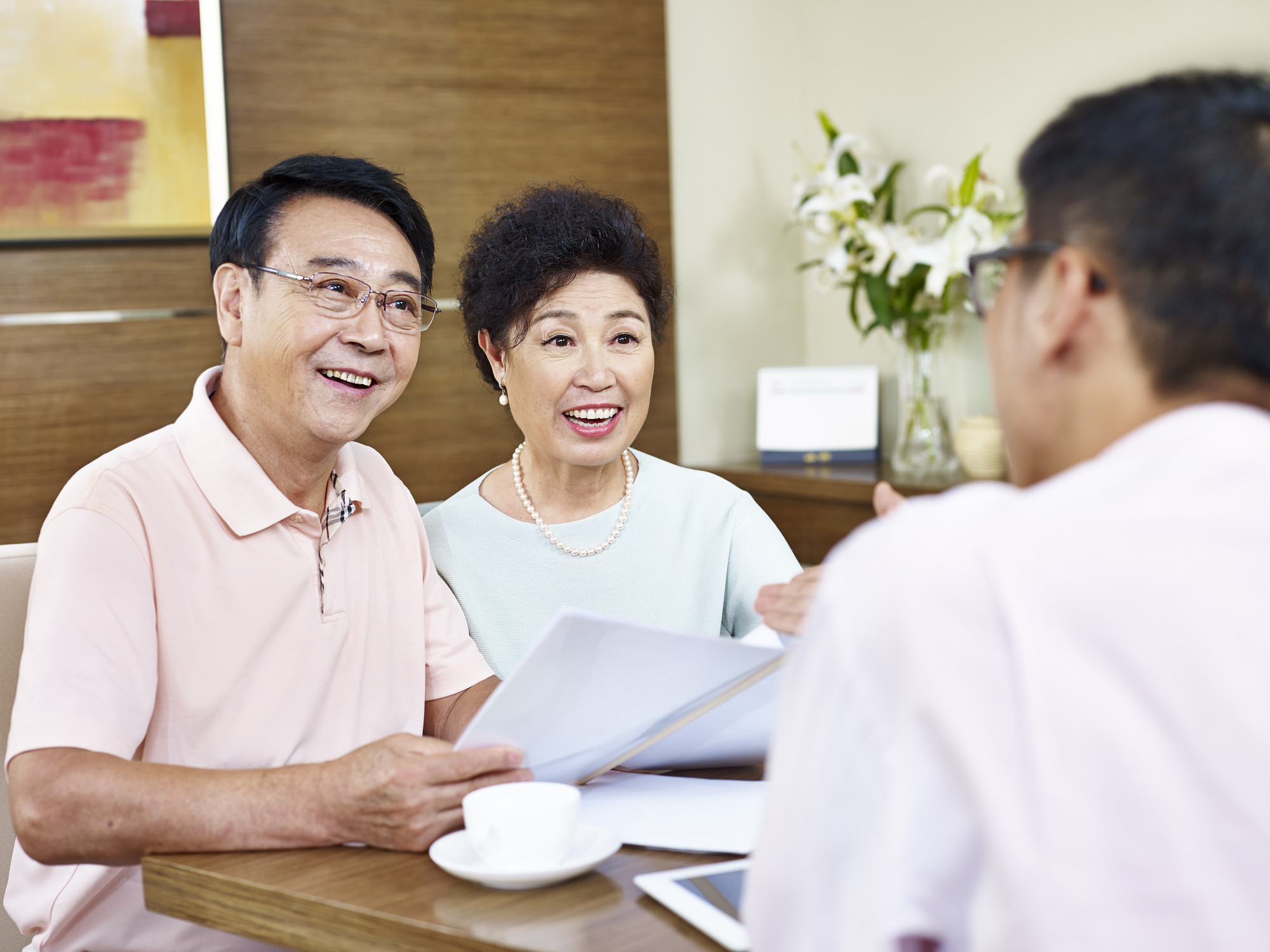 Stock Image of Senior Asian Couple Meeting with Realtor Who Is Showing Them a Piece of Paper
