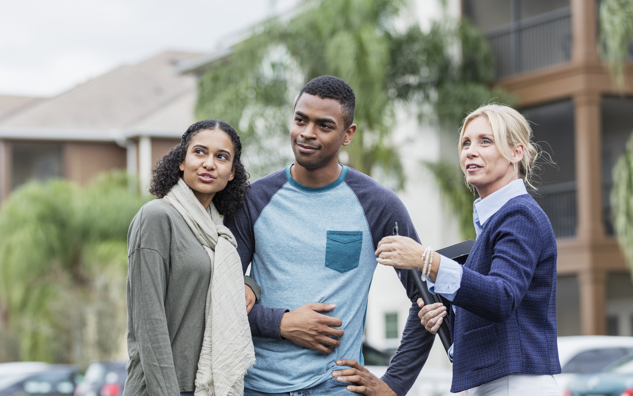 Stock Photo of a Couple and a Real Estate Agent Standing Outside Looking Toward a Home