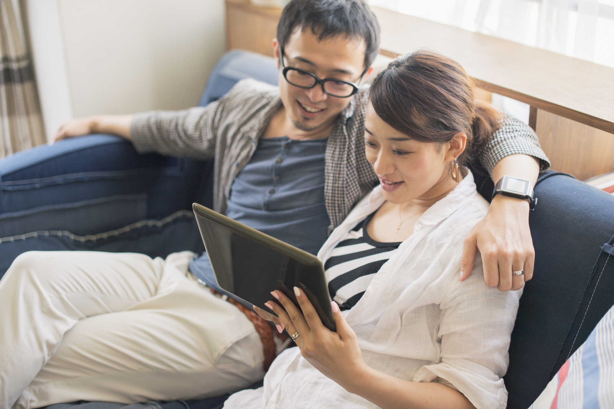 Stock Photo of Man and Woman Looking At a Tablet And Smiling