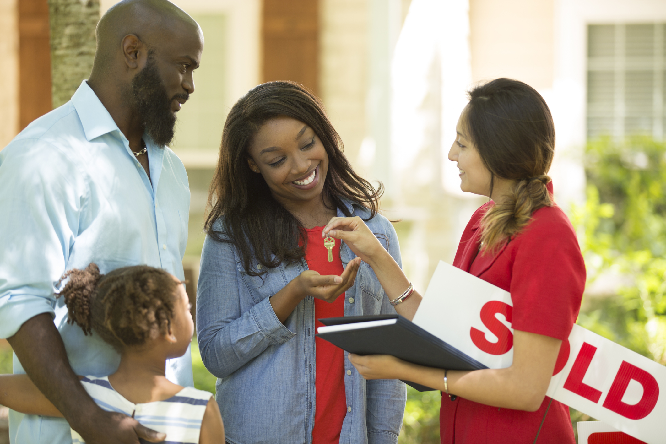 Stock Photo of Man Woman and Child and Realtor Handing Keys To the Smiling Woman