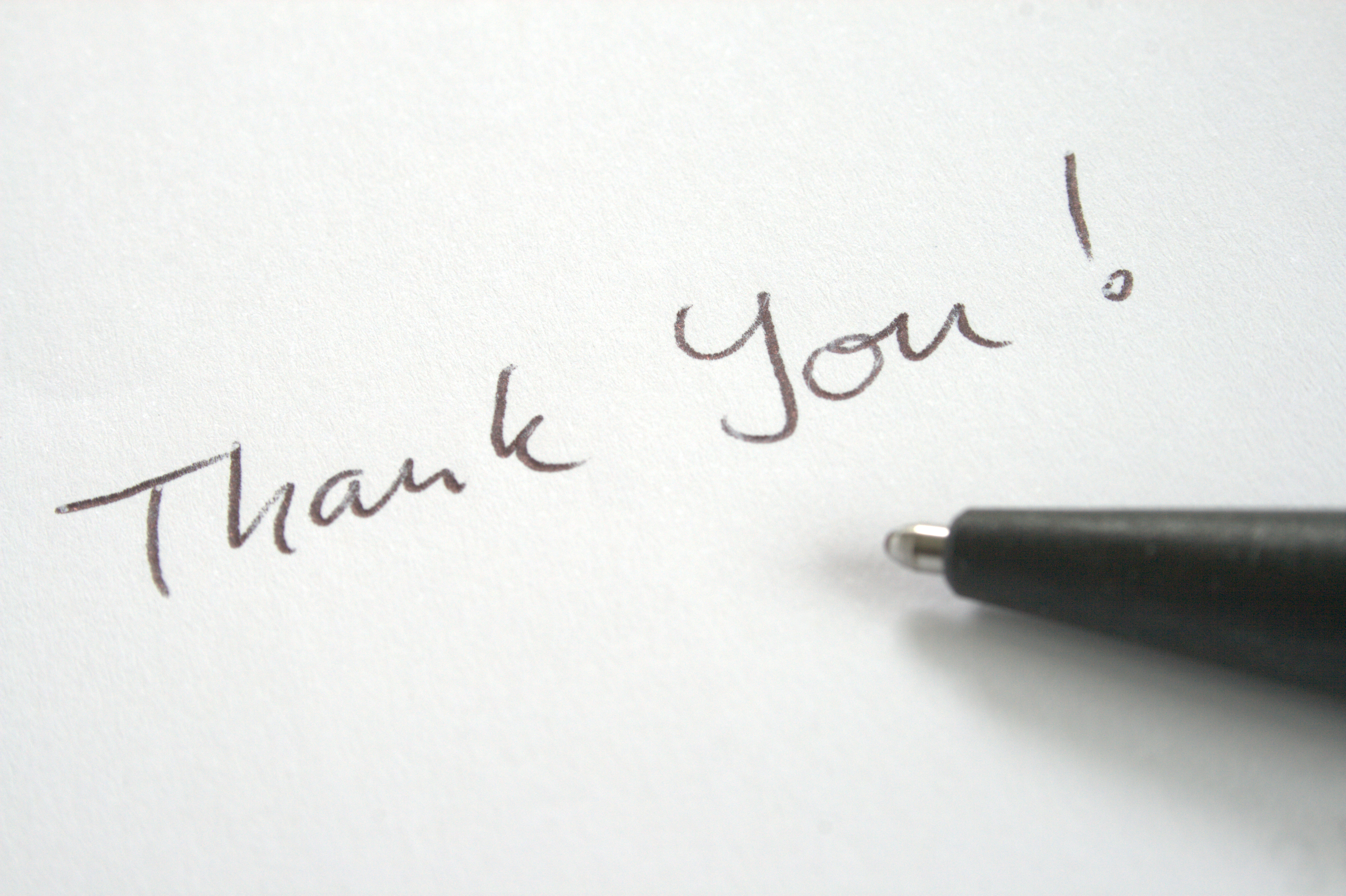 Stock Photo of Pen Writing the Words Thank You on a Piece Of Paper
