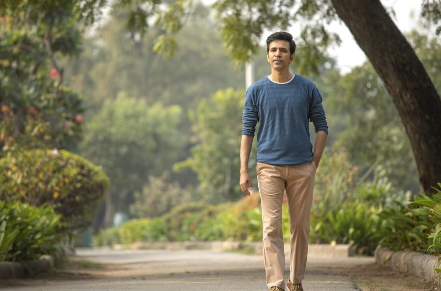 man walking in park with one hand in his pocket