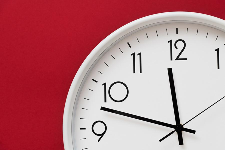 stock image of a close up shot of an analog clock with a bright red background