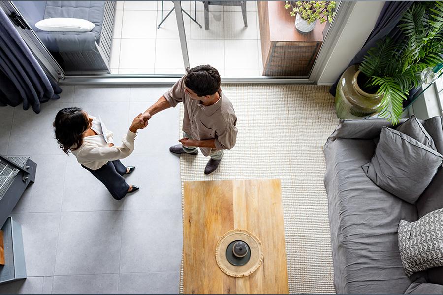 stock overhead image of man and woman standing in a modern living room shaking hands
